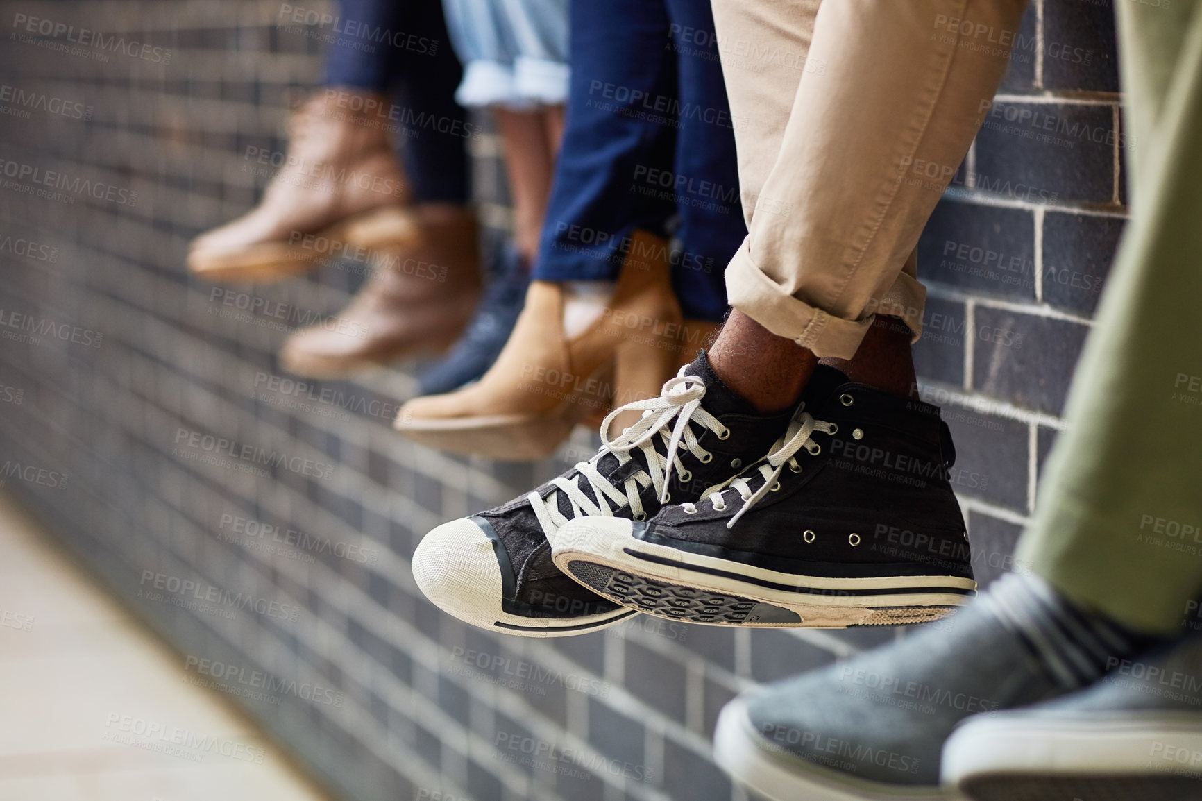 Buy stock photo Brick wall, student sneakers and friends outdoor on university campus together with feet. Relax, urban youth and foot at college with people legs ready for education, study and shoes while sitting