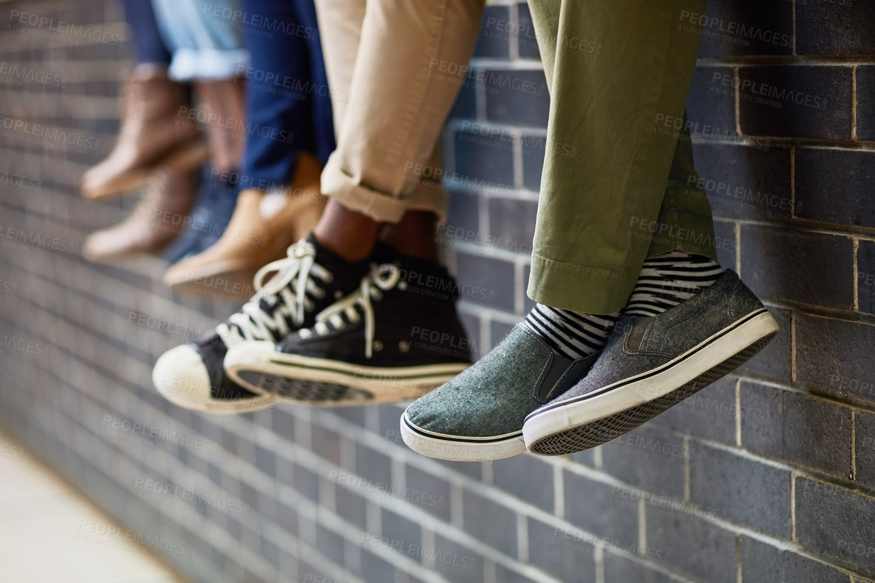 Buy stock photo Brick wall, students feet and friends outdoor on university campus together with sneakers. Relax, youth and foot at college with people legs ready for education, study and urban shoes while sitting