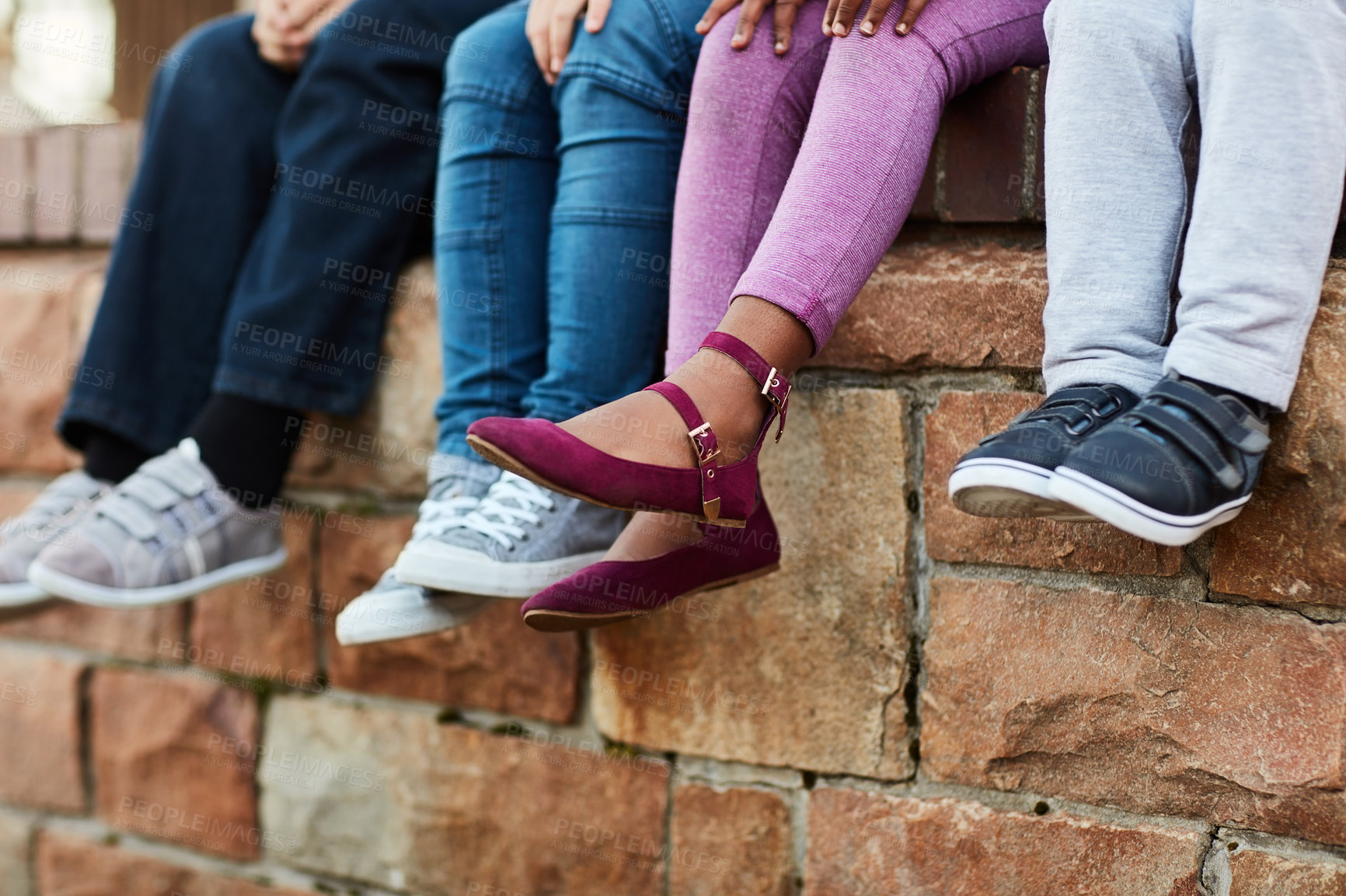 Buy stock photo Cropped shot of unrecognizable elementary school kids sitting on a brick wall outside