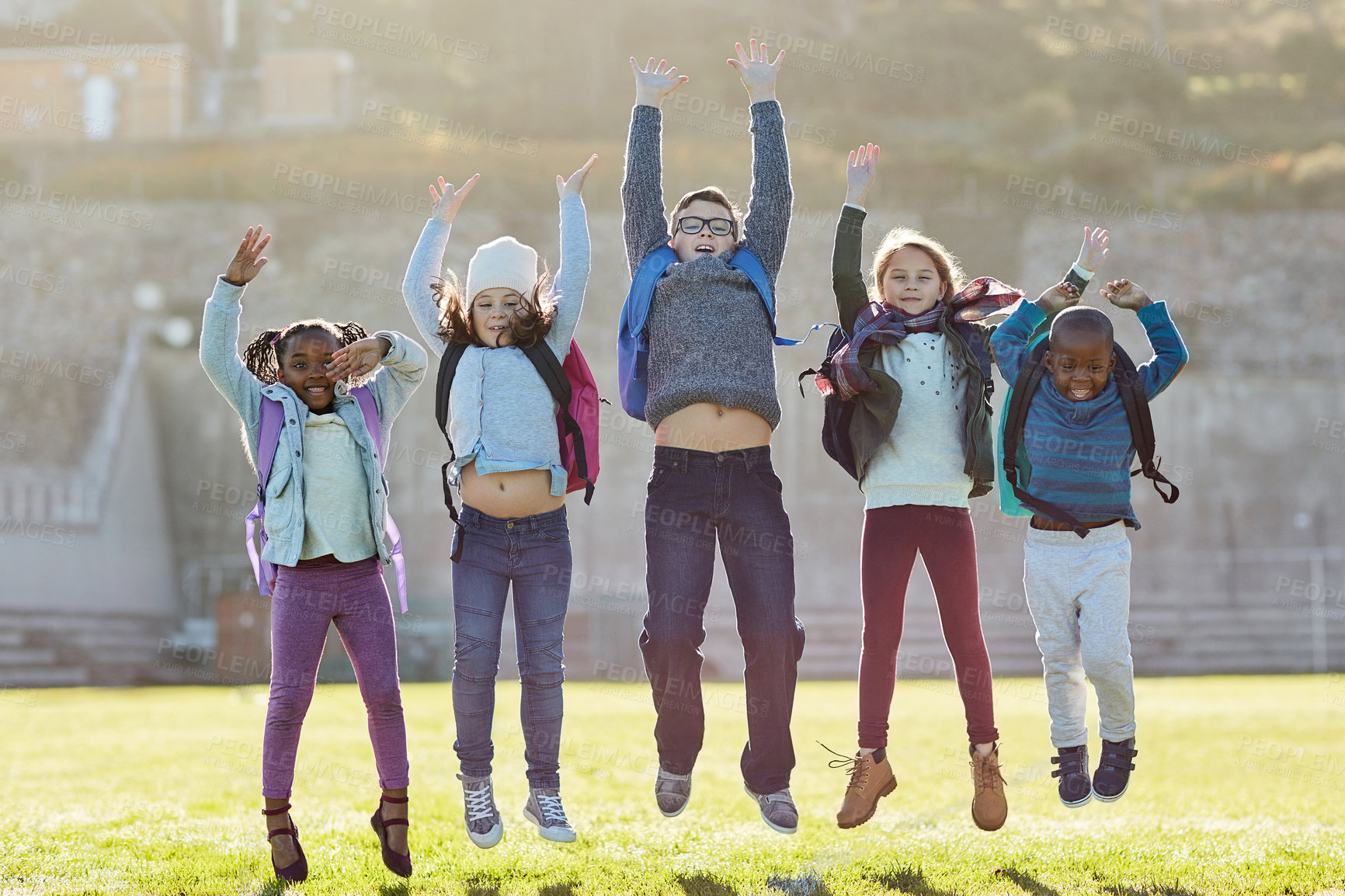 Buy stock photo School, kids and portrait with jump by field for freedom, summer break and beginning of vacation. Excited, children and backpack with celebration on grass for education, holiday and end of semester