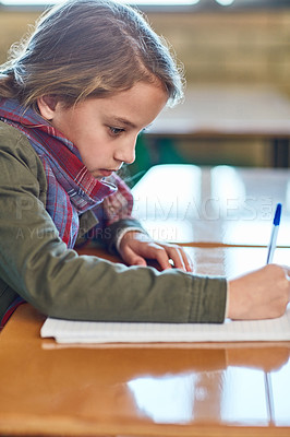 Buy stock photo Cropped shot of an elementary school girl doing her school work in the classroom