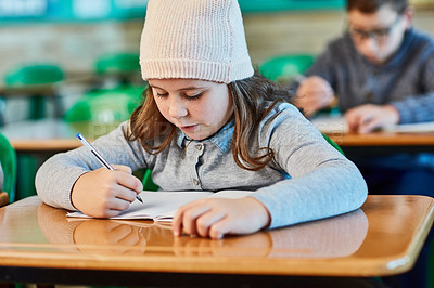 Buy stock photo Cropped shot of an elementary school girl doing school work in the classroom