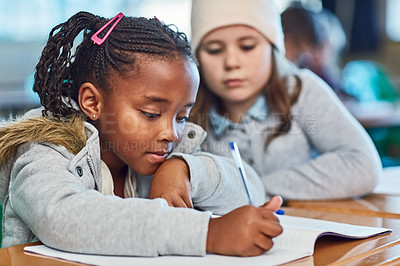 Buy stock photo Cropped shot of elementary school girls doing school work together in the classroom