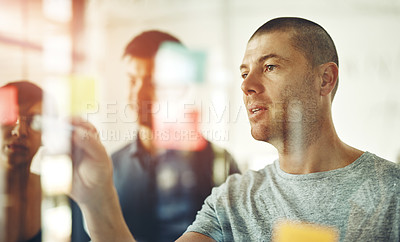 Buy stock photo Businessman planning ideas on a transparent board thinking, brainstorming and working on strategy for a group project. Group of busy and organized creative people working together using sticky notes