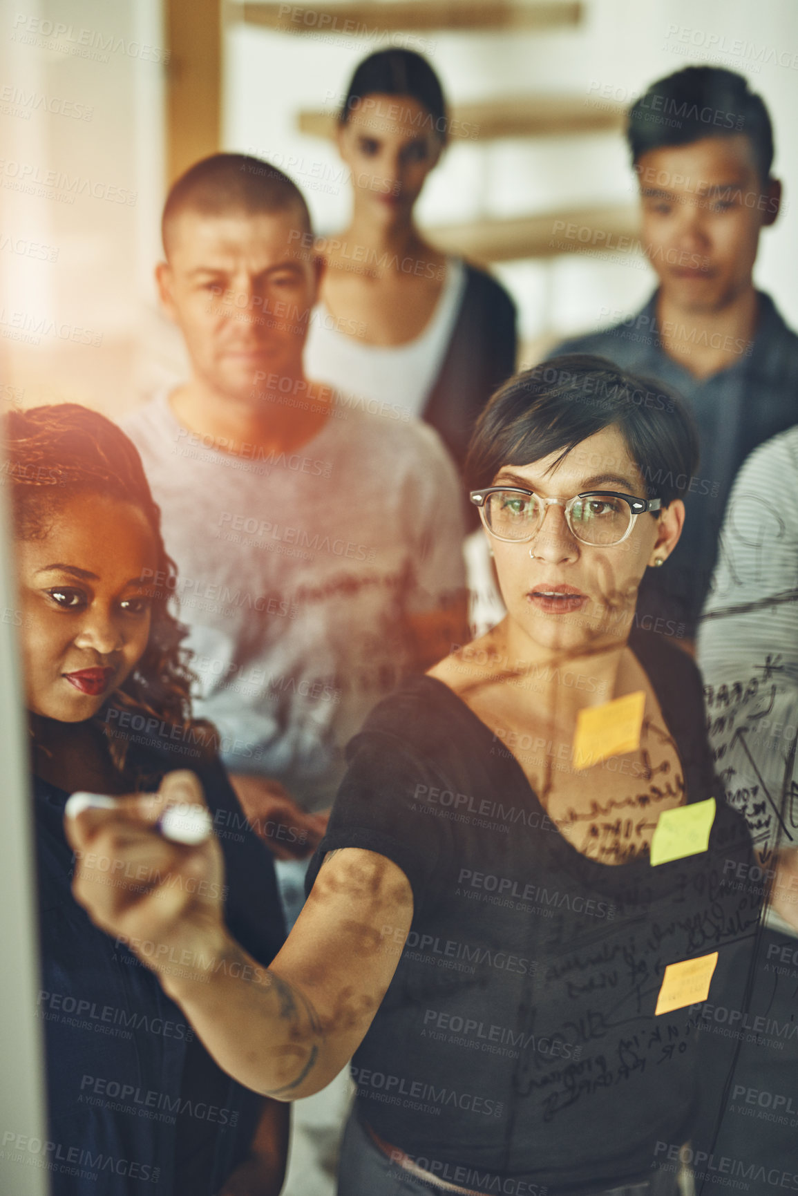 Buy stock photo Lady manager talking and standing in the meeting with the team. Writing notes on boardroom glass wall. Businesspeople, diverse colleagues and coworkers brainstorm together in the office.