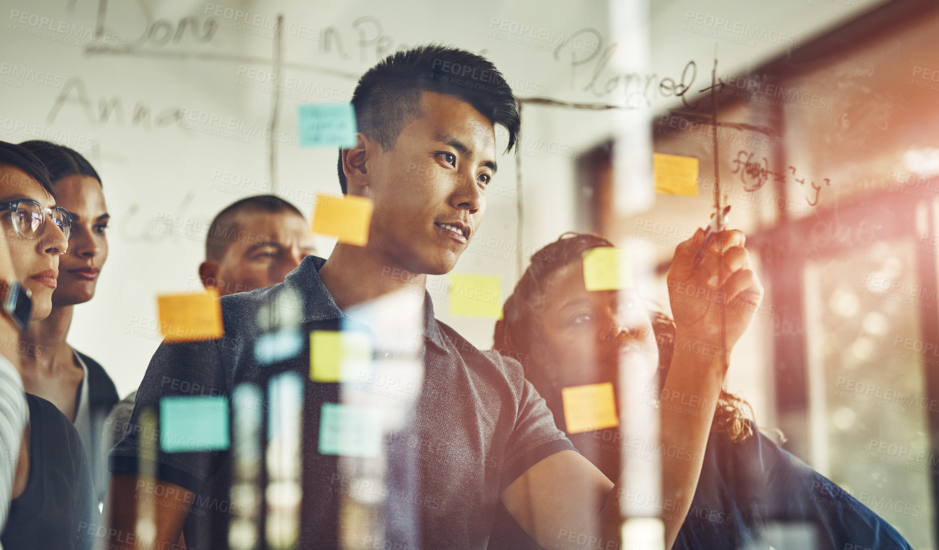 Buy stock photo Cropped shot of a group of young designers using sticky notes during a brainstorming session