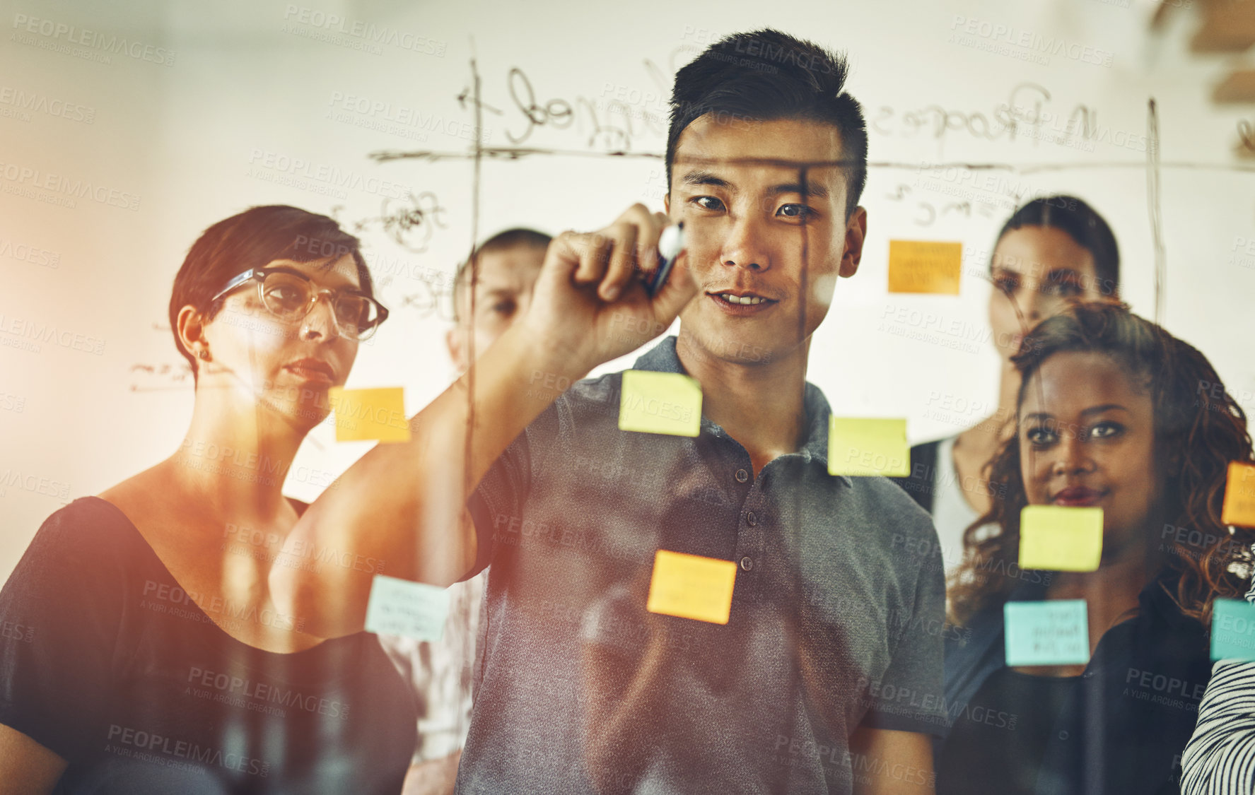 Buy stock photo Team leader planning and writing on sticky notes while brainstorming, talking and sharing vision or ideas. Diverse group of creative business people meeting together to market new startup company