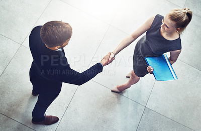 Buy stock photo High angle shot of two unrecognizable businesspeople shaking hands in a corporate office