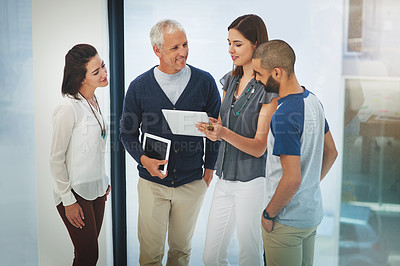Buy stock photo Cropped shot of a group of colleagues having a conversation over a tablet in their office