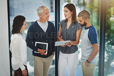 Buy stock photo Cropped shot of a group of colleagues having a conversation over a tablet in their office