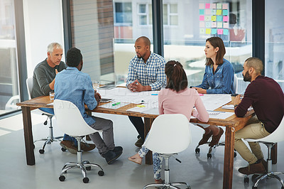 Buy stock photo Full length shot of a group of architects looking over blueprints during a meeting in the boardroom