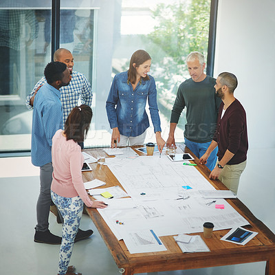Buy stock photo High angle shot of a group of architects looking over blueprints during a meeting in the boardroom