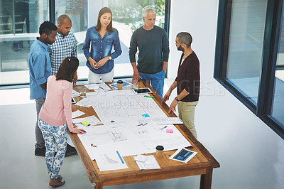 Buy stock photo High angle of a group of architects looking over blueprints during a meeting in the boardroom