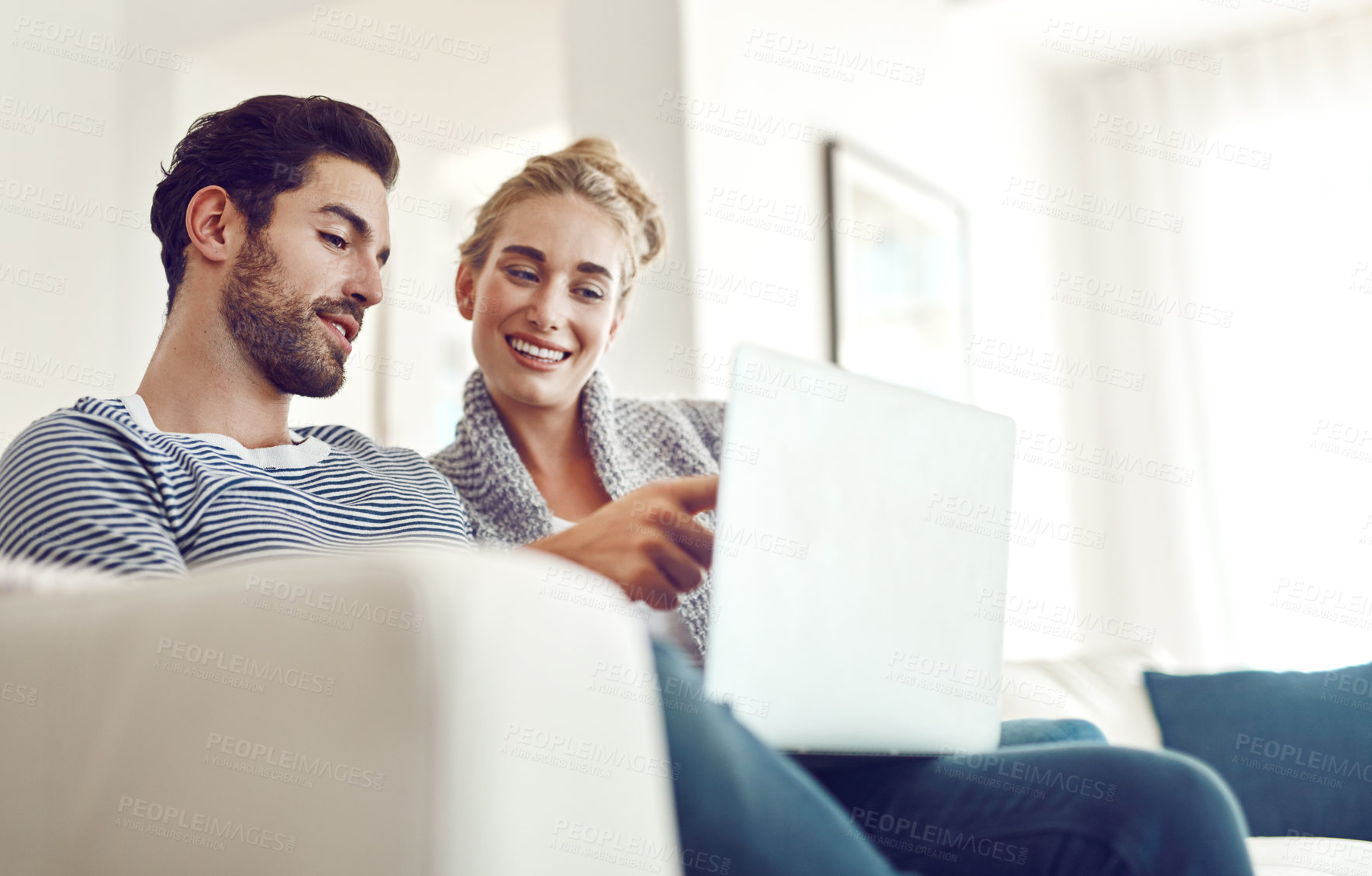 Buy stock photo Shot of a young couple using a laptop on their sofa at home