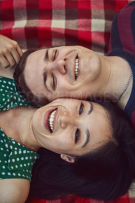 Buy stock photo Shot of a happy young couple relaxing together on a picnic blanket