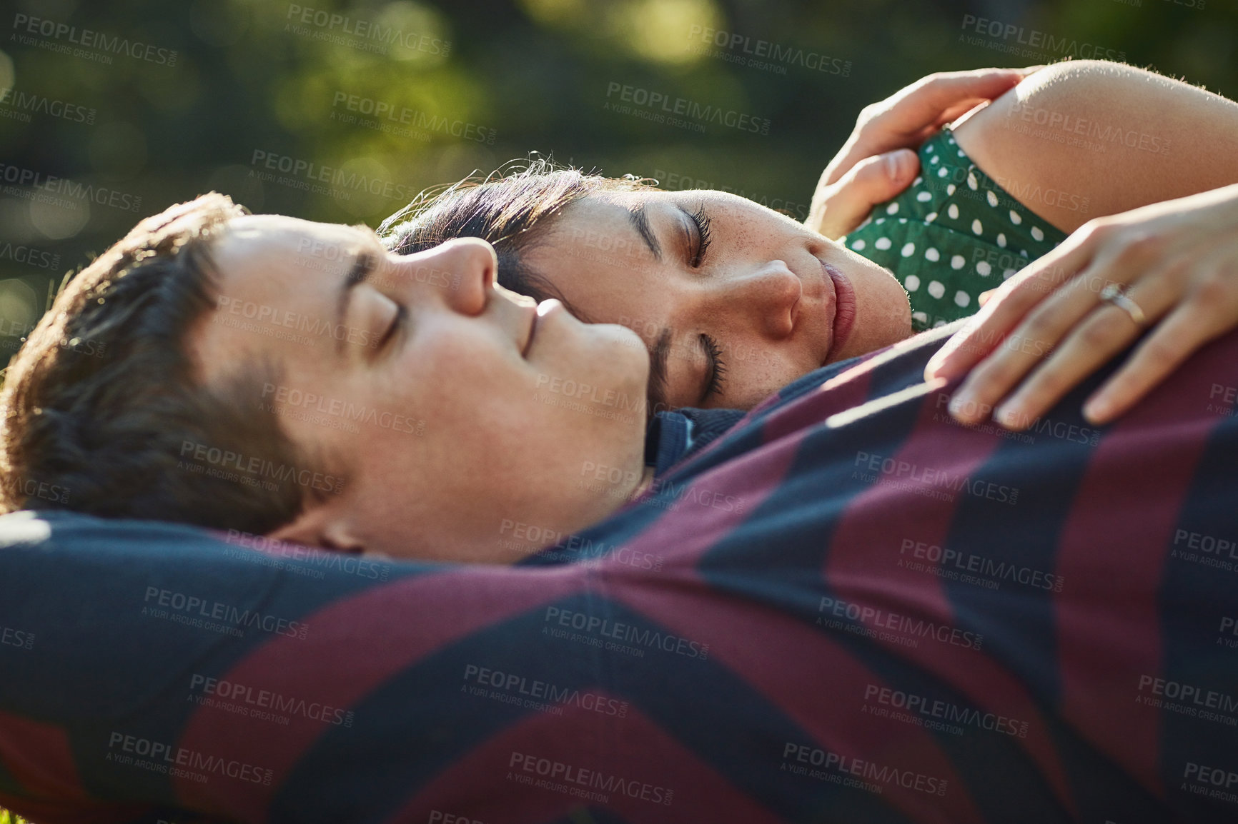 Buy stock photo Shot of an affectionate young couple enjoying an afternoon nap in the park
