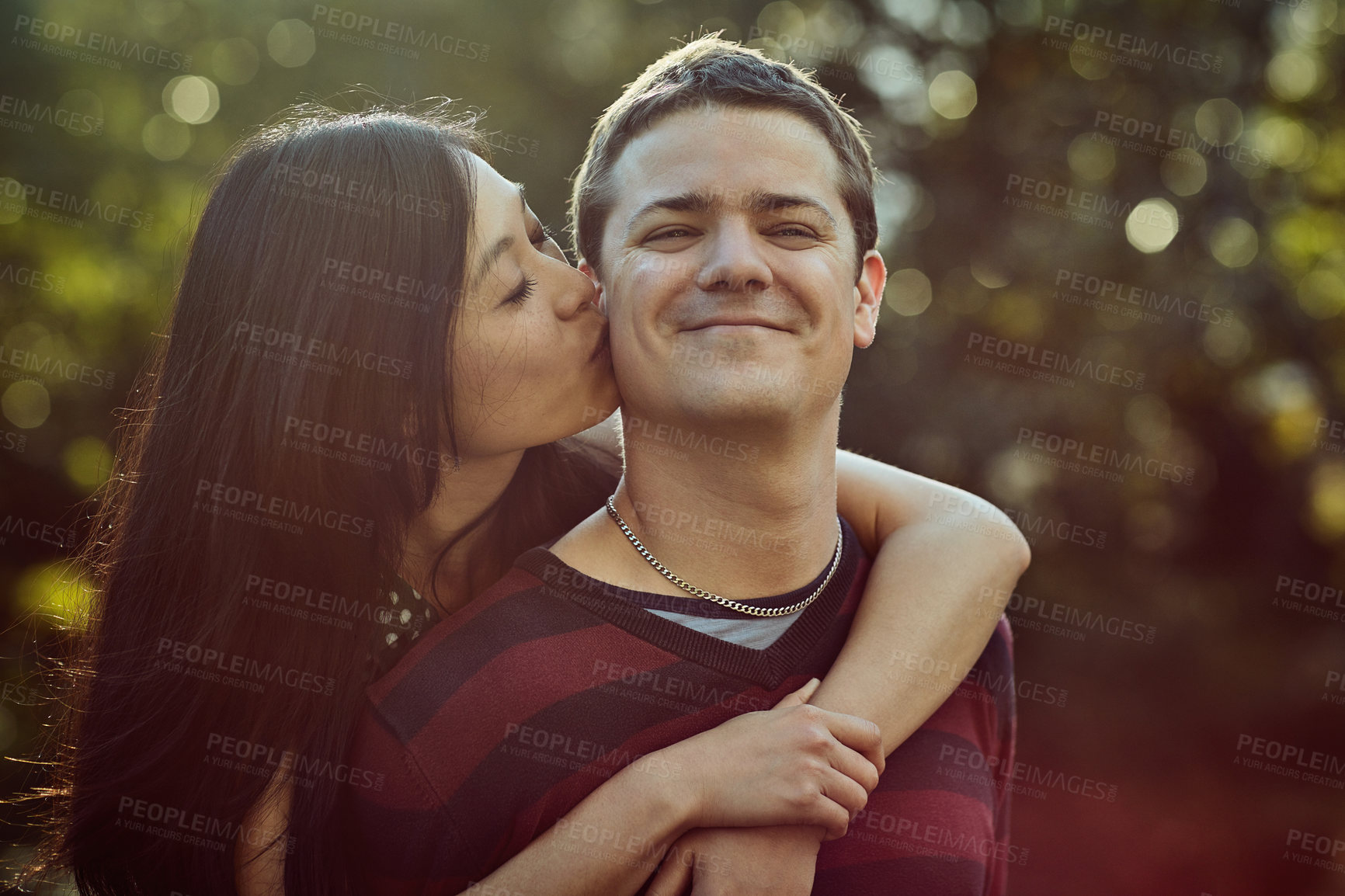 Buy stock photo Shot of an affectionate young couple enjoying a piggyback ride outdoors