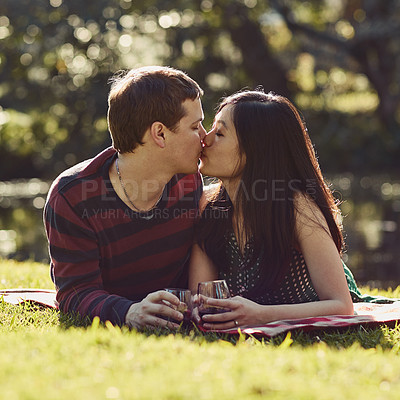 Buy stock photo Shot of an affectionate young couple having a romantic picnic in the park