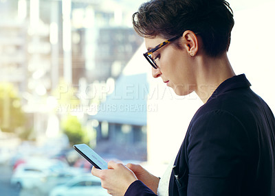 Buy stock photo Cropped shot of an attractive young businesswoman using a mobile phone while standing on her office balcony