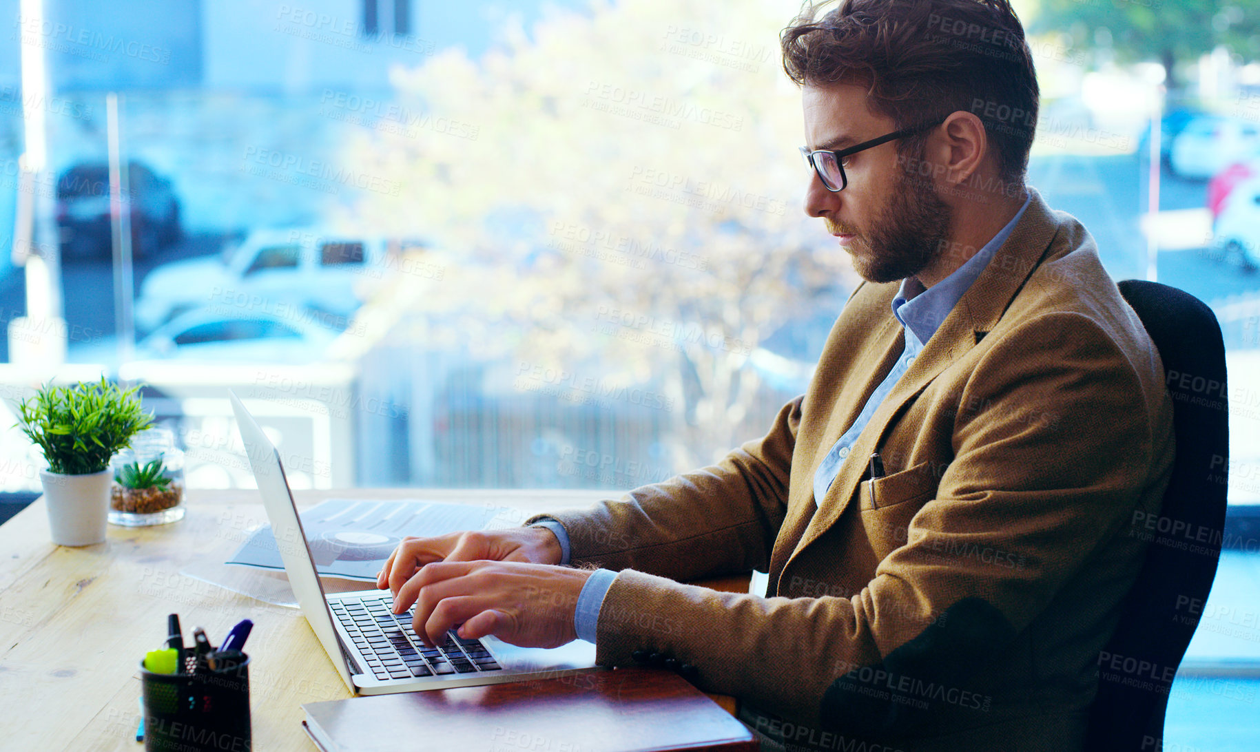 Buy stock photo Cropped shot of a handsome businessman working on a laptop while sitting at his desk in the office