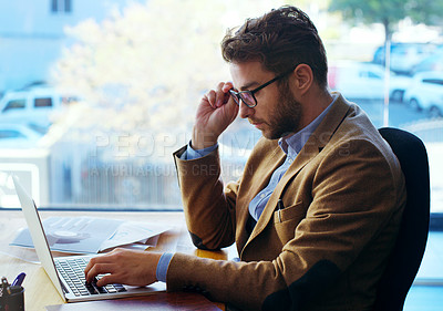Buy stock photo Cropped shot of a handsome businessman working on a laptop while sitting at his desk in the office