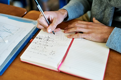 Buy stock photo High angle shot of an unrecognizable university student writing in his notebook while sitting in class