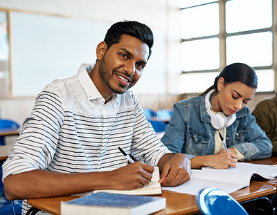 Buy stock photo Cropped portrait of a handsome young university student taking notes while sitting in class