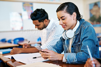 Buy stock photo Cropped shot of an attractive young university student sending a text message while sitting in class