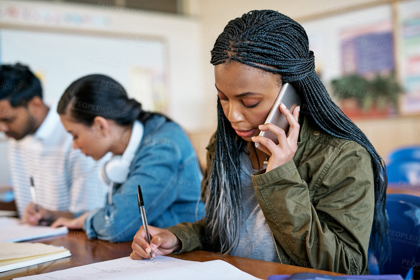 Buy stock photo Cropped shot of an attractive young university student taking a phonecall while sitting in class