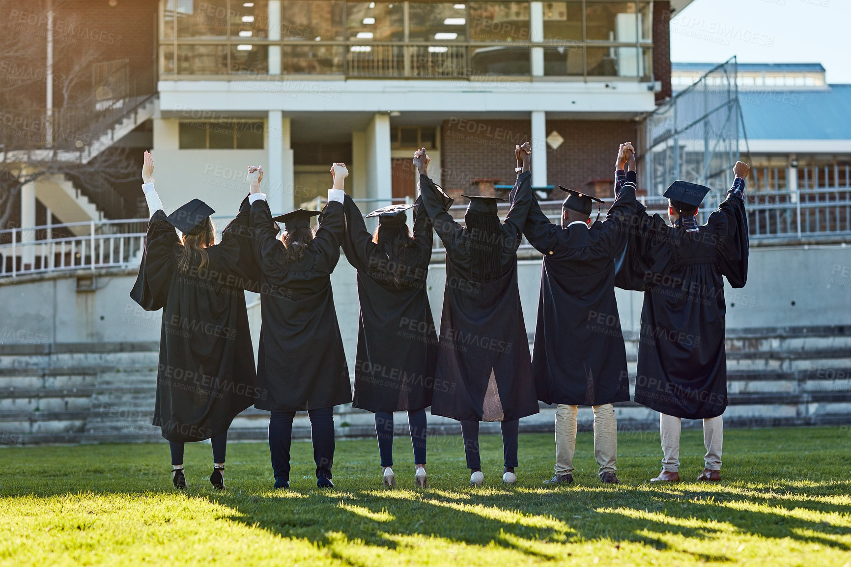 Buy stock photo Holding hands, university and back of friends for graduation, ceremony and academic success. College, diversity and men and women on campus with achievement for education, learning and studying