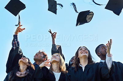 Buy stock photo Shot of a group of students throwing their hats in the air on graduation day