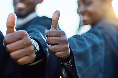 Buy stock photo Closeup shot of two unrecognizable students showing thumbs up on graduation day