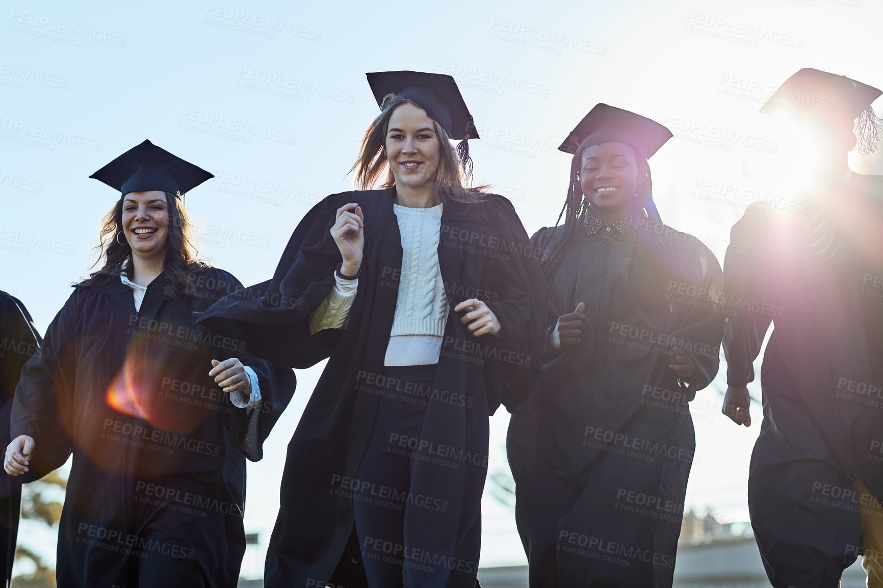 Buy stock photo Excited, students and group of people at graduation with smile, happy achievement and education. University, women and men on campus with success, diversity or friends walking at award ceremony