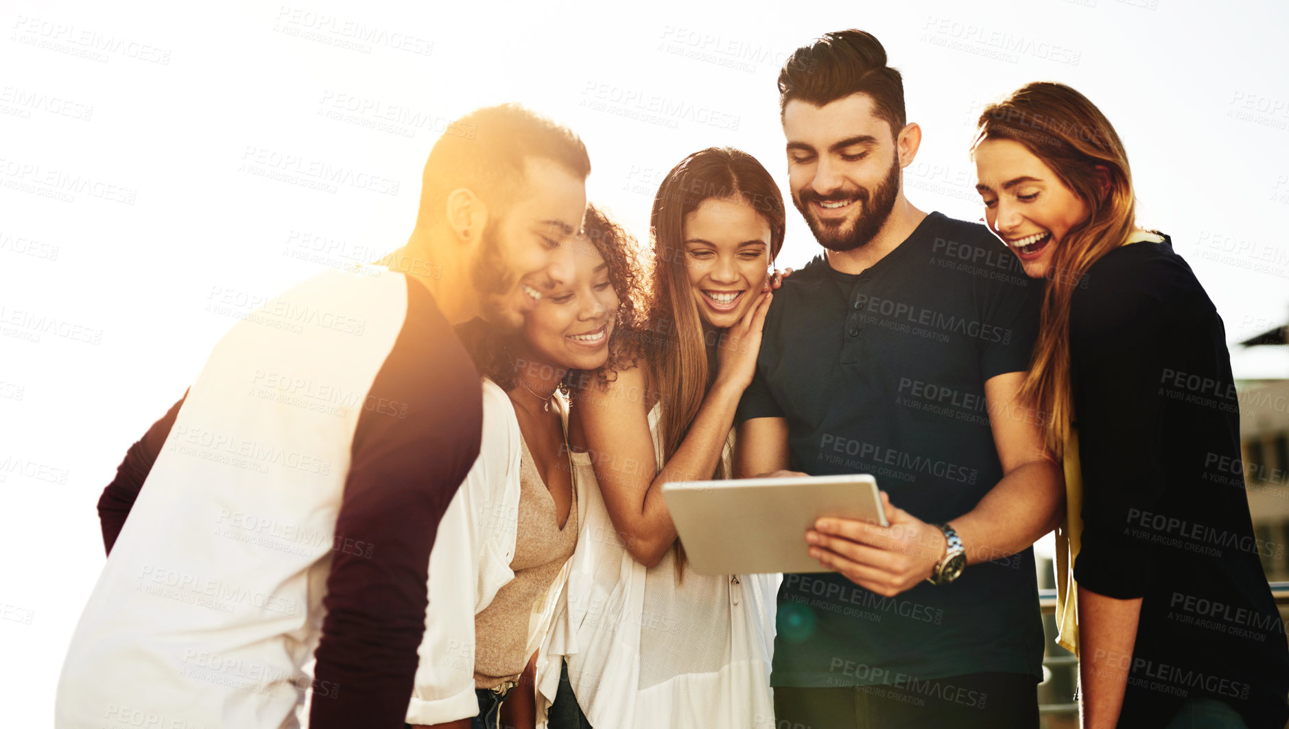 Buy stock photo Shot of young friends using a tablet outside