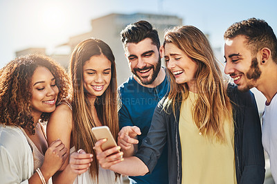 Buy stock photo Shot of young friends using a smartphone outside
