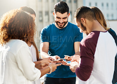 Buy stock photo Shot of young friends using smartphones outside