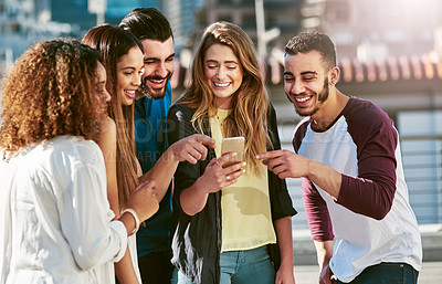 Buy stock photo Shot of young friends using a smartphone outside