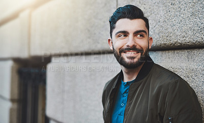 Buy stock photo Cropped shot of a handsome young man standing against a wall while out in the city