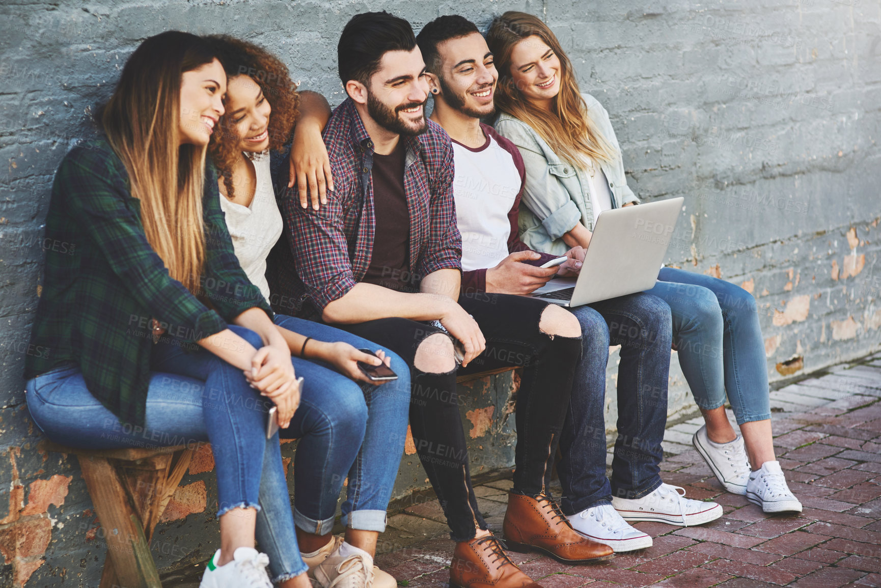 Buy stock photo Shot of a group of young friends using their wireless devices together outdoors