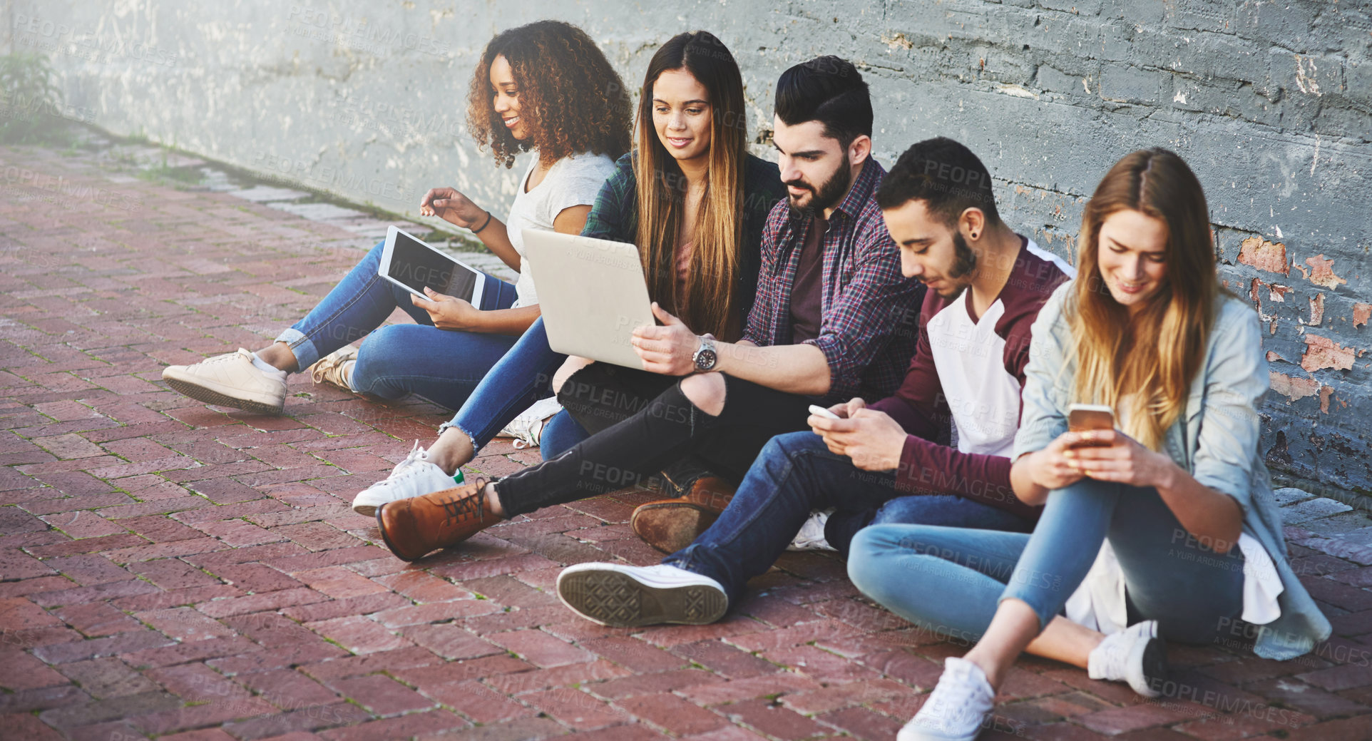 Buy stock photo Shot of a group of young friends using their wireless devices together outdoors