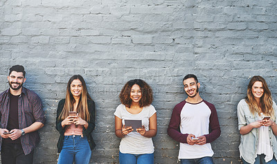 Buy stock photo Portrait of a group of young people using their wireless devices together outdoors