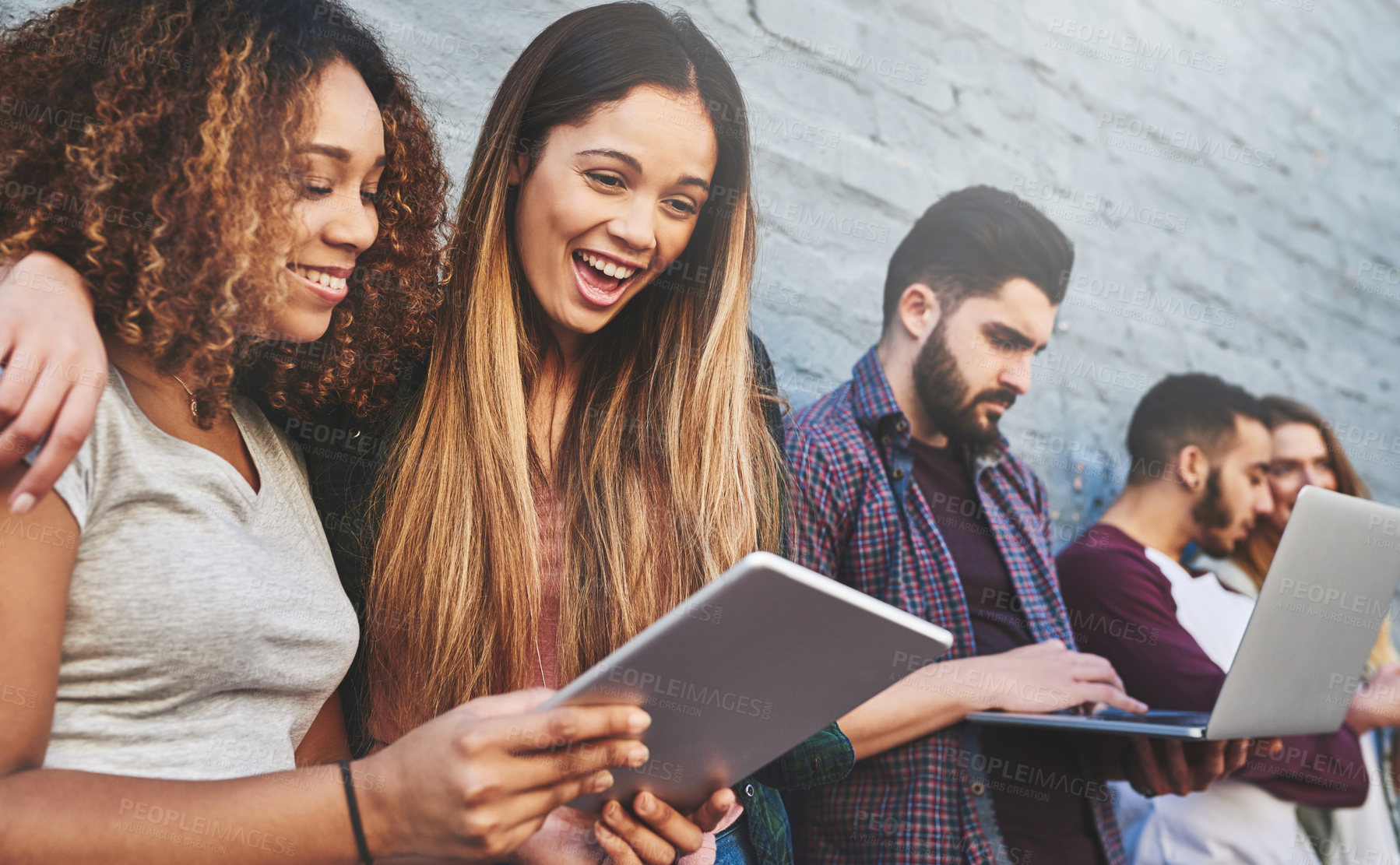 Buy stock photo Shot of a group of young friends using their wireless devices together outdoors