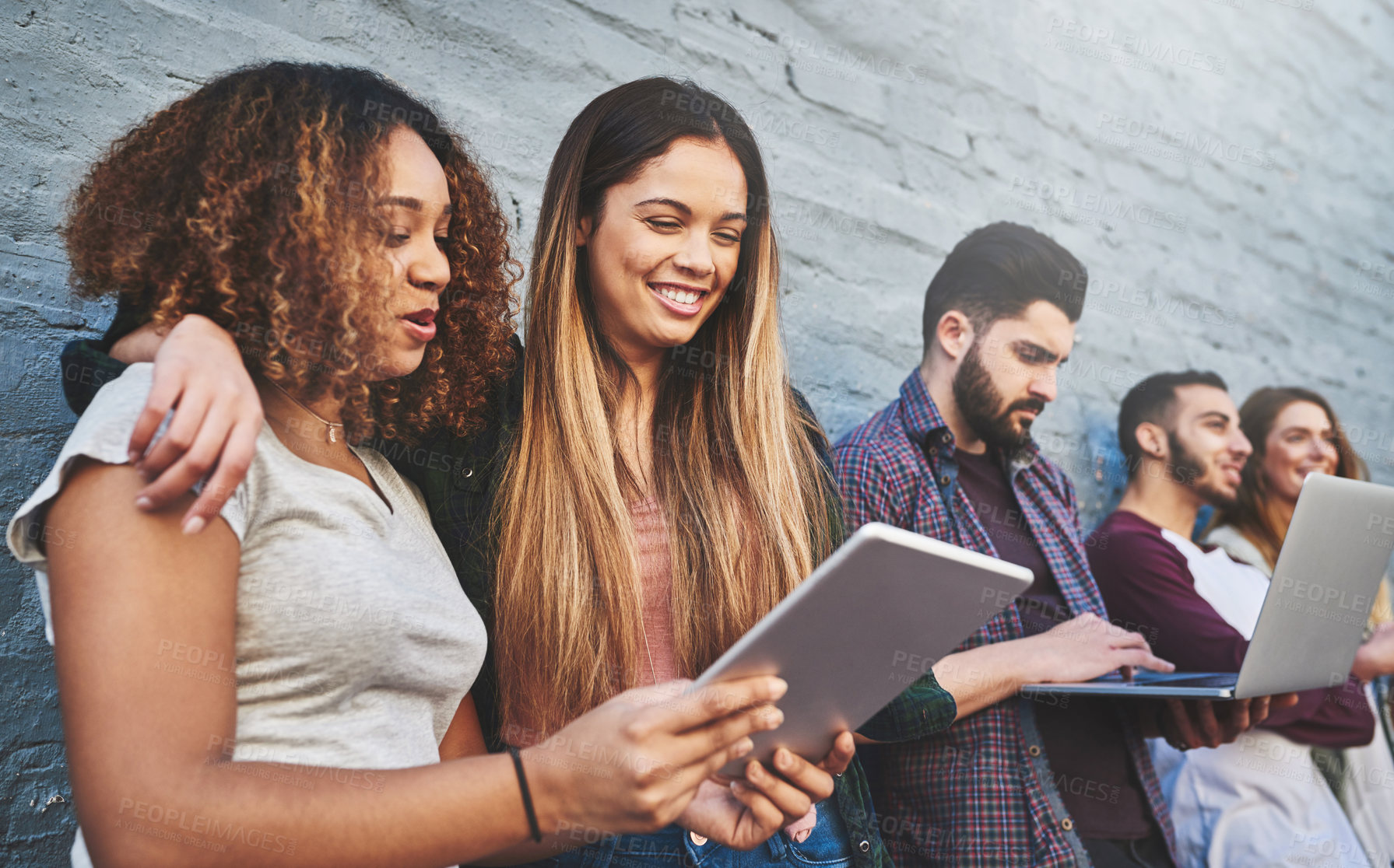 Buy stock photo Shot of a group of young friends using their wireless devices together outdoors