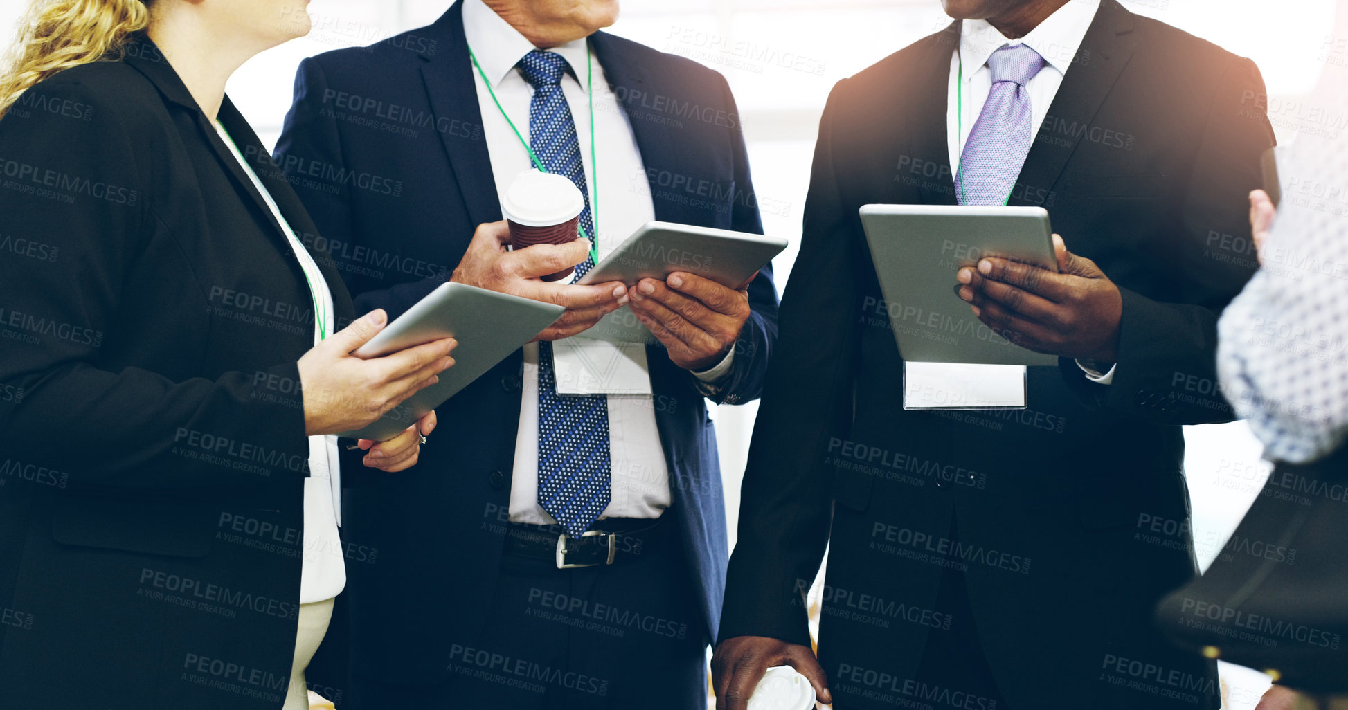 Buy stock photo Cropped shot of a group of unrecognizable businesspeople standing in a huddle with digital tablets in hand