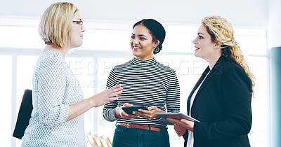 Buy stock photo Cropped shot of three corporate businesswomen standing in a huddle with digital tablets in hand