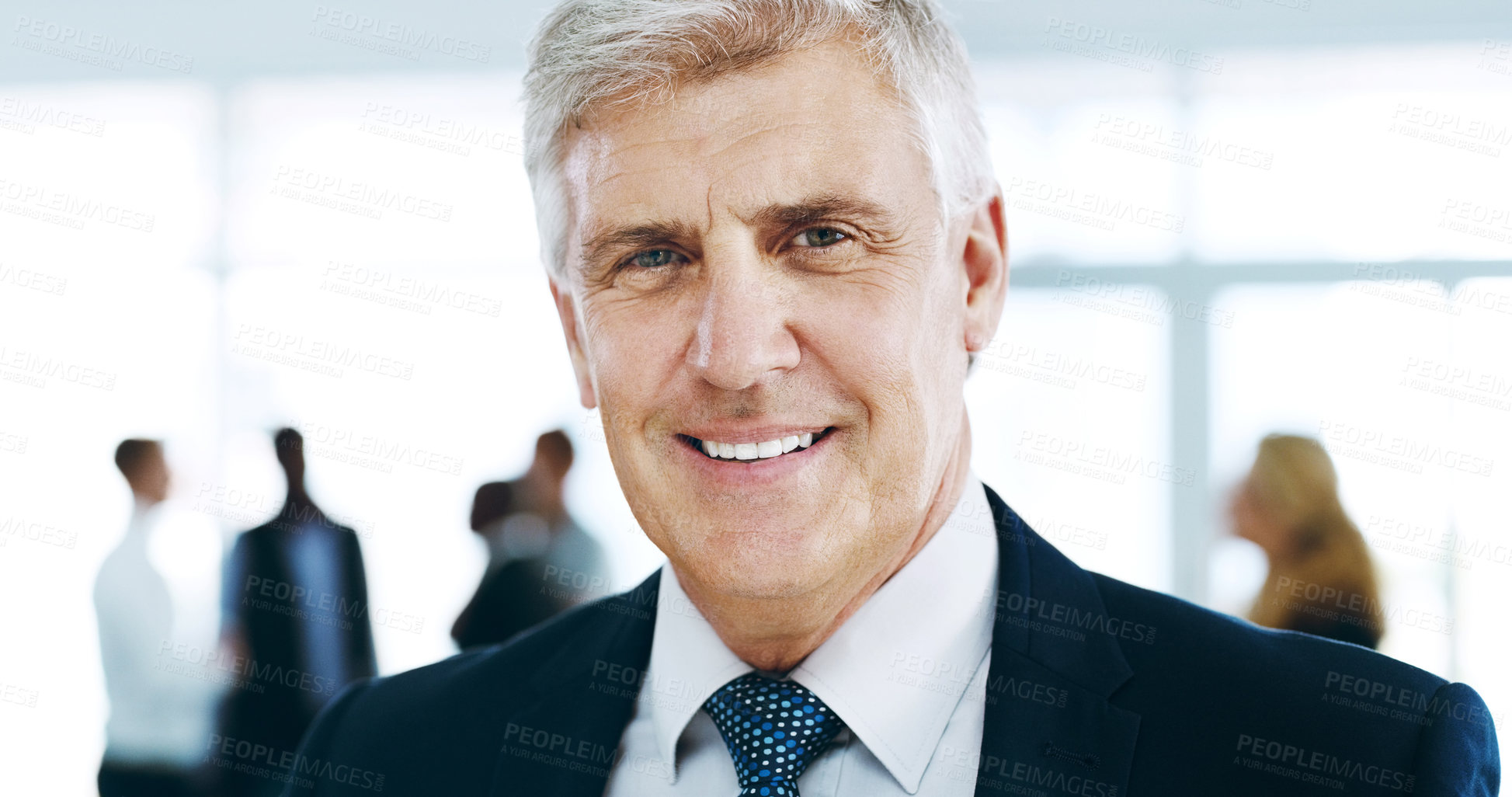 Buy stock photo Cropped portrait of a handsome mature businessman standing in the office with his colleagues in the background