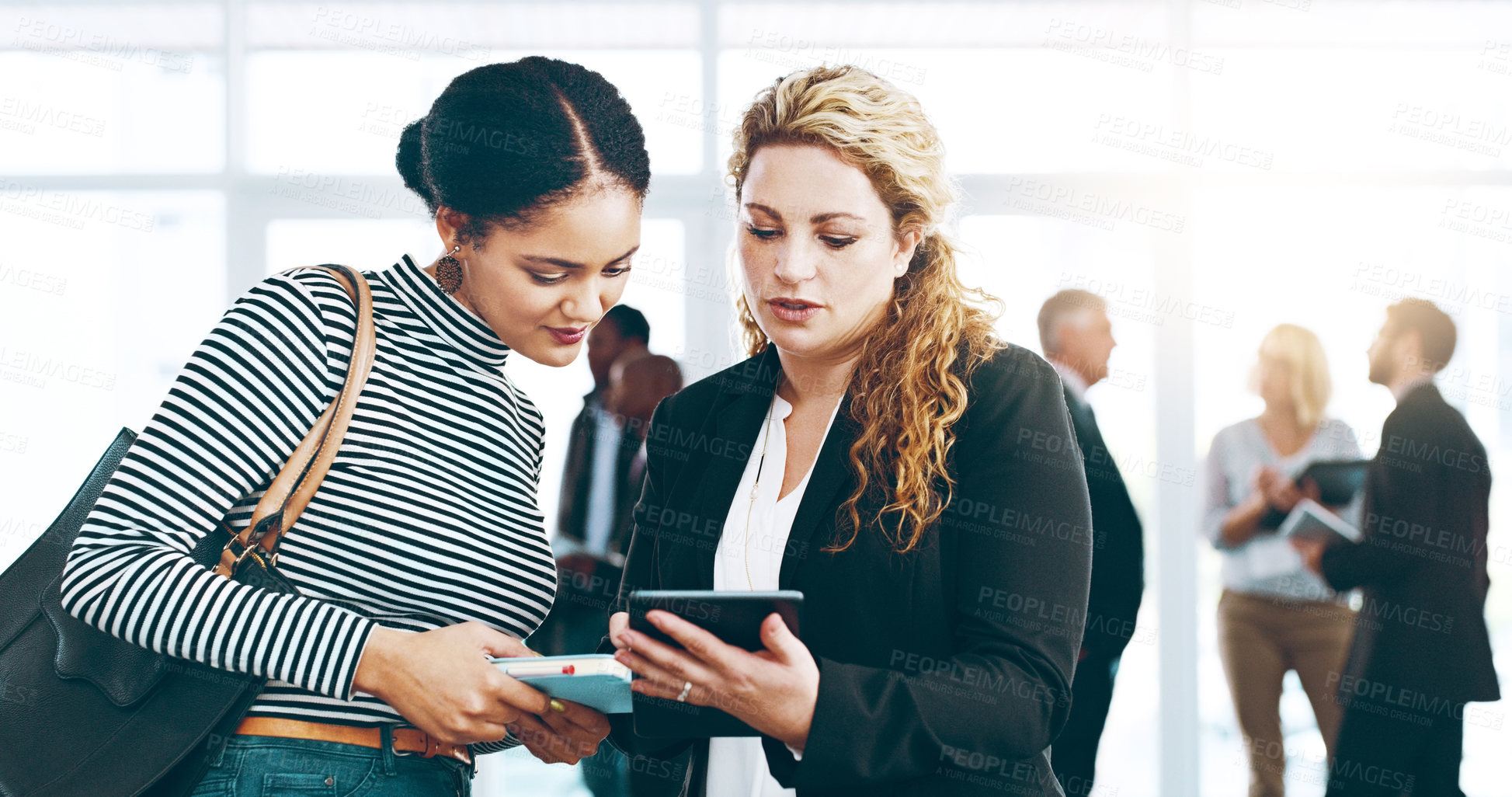 Buy stock photo Cropped shot of two corporate businesswomen standing in a huddle with digital tablets in hand