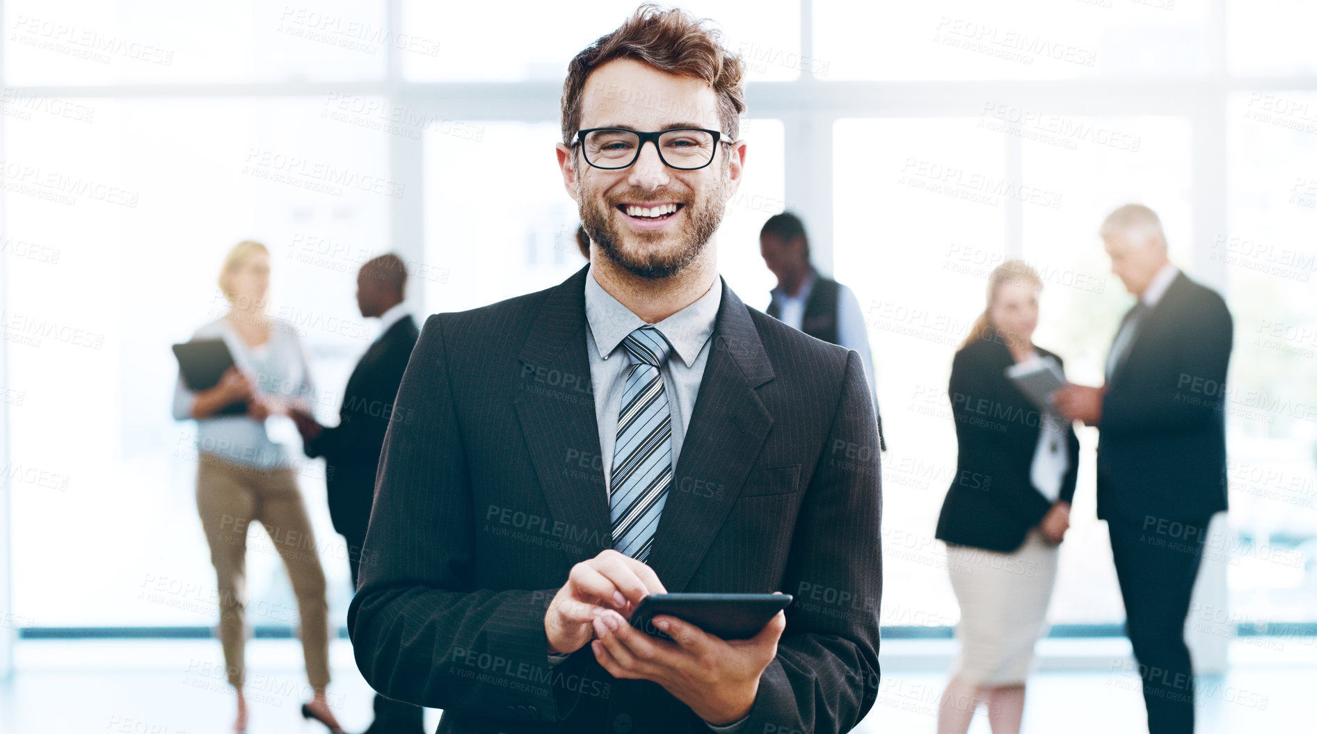 Buy stock photo Cropped portrait of a handsome businessman using a tablet in the office with his colleagues in the background