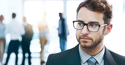 Buy stock photo Cropped shot of a handsome businessman standing in the office with his colleagues in the background