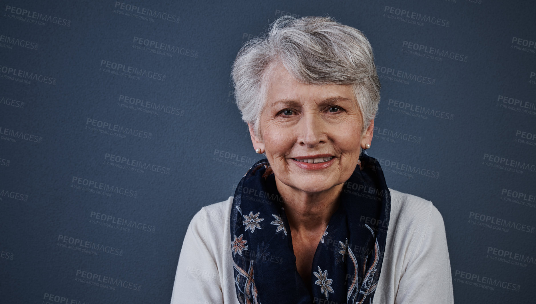 Buy stock photo Studio shot of a cheerful elderly woman sitting down and looking straight into the camera while smiling